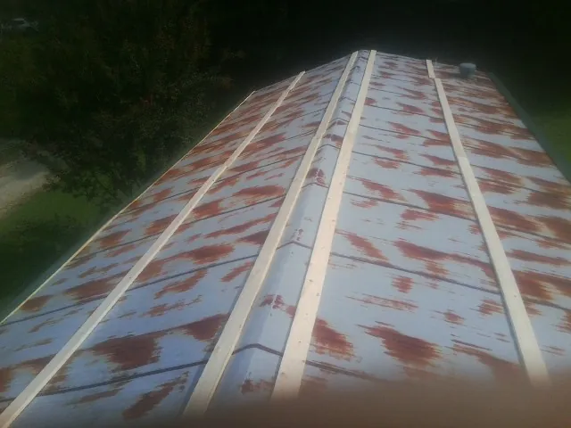 Rusted metal roof panels with new wood purlins before replacement — Storm Damage Roof Repair in Claiborne by Roofing Brothers