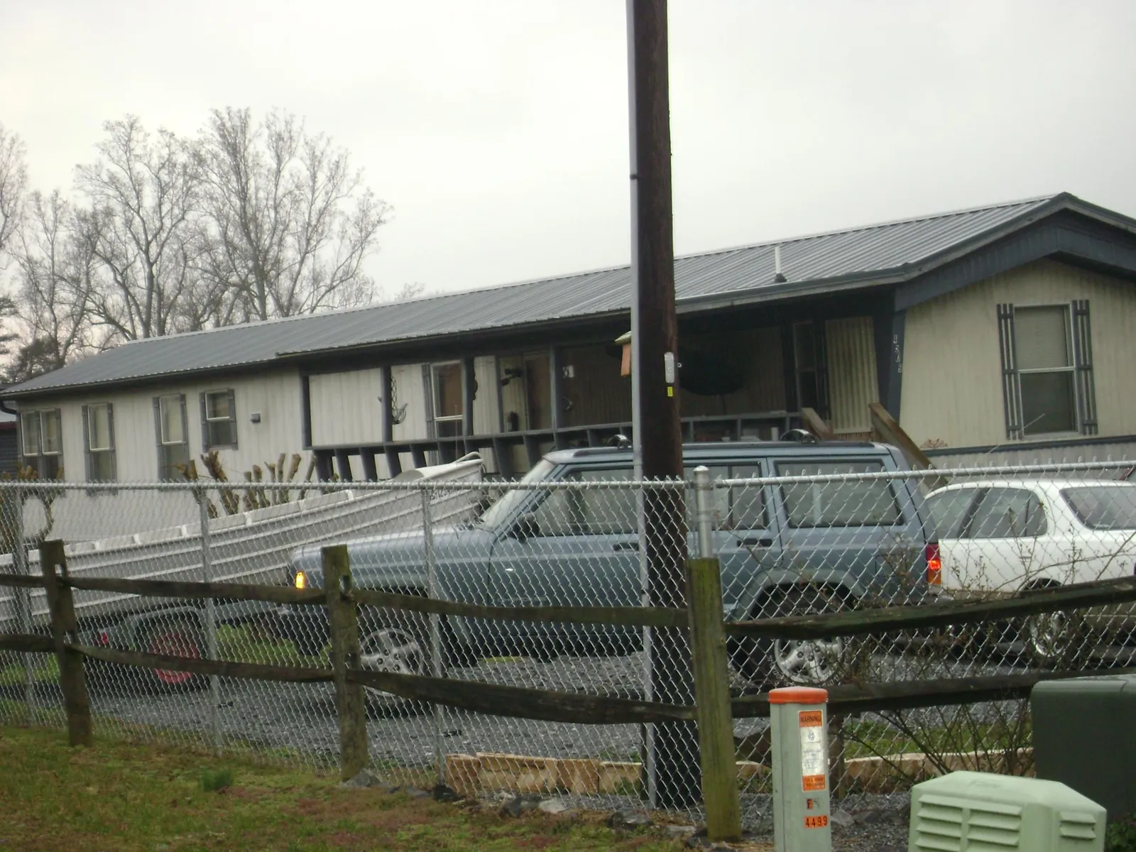 Dark metal roof on a long single story building behind a chain link fence in Claiborne