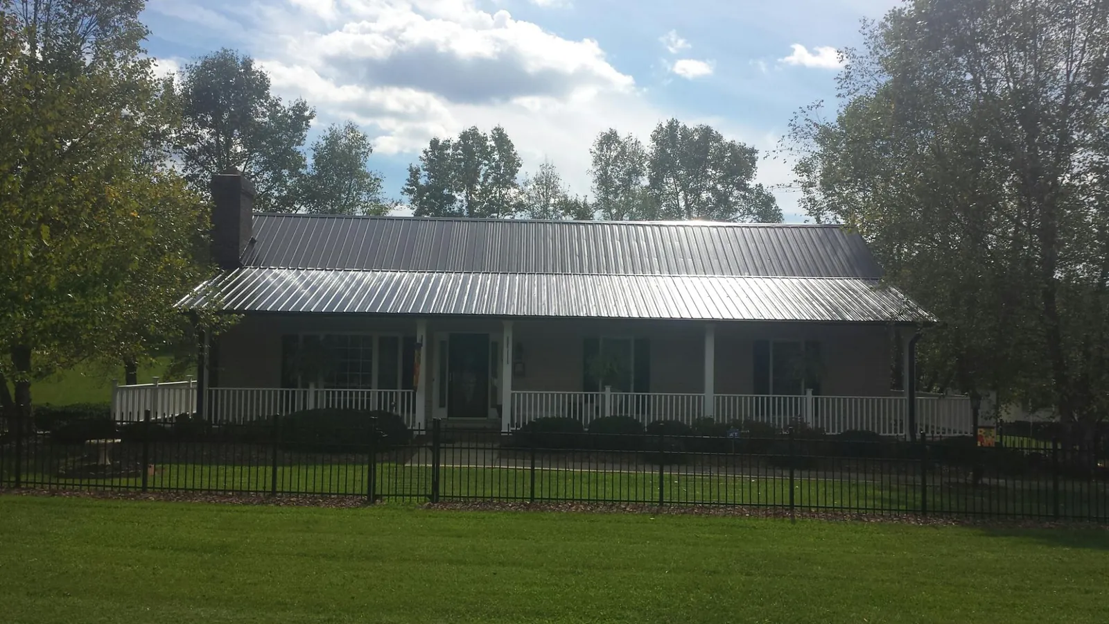 Gray metal roof on a brick ranch with a full width front porch — Gutter Guard Installation work by our crew in Claiborne