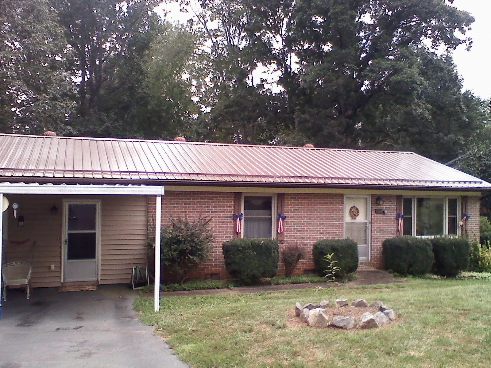 Bronze metal roof and carport on a brick ranch home — Roof Repair work by our crew in Claiborne