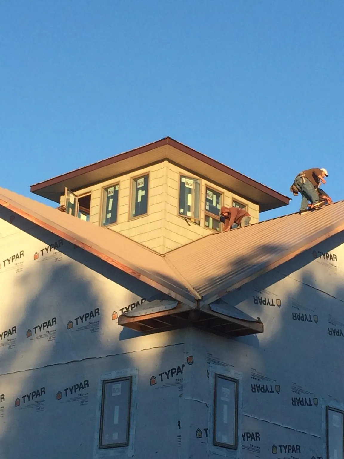 Roofers working around a rooftop cupola on a new metal roof at sunset — Roof Waterproofing in Claiborne by Roofing Brothers